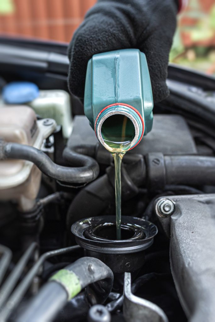 Mechanic pouring engine oil into a vehicle - Car Servicing Mitcham